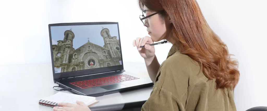 A model researching on a laptop (show laptop screen - a photo of San Sebastian Cathedral in Bacolod City - The City Of Smiles)